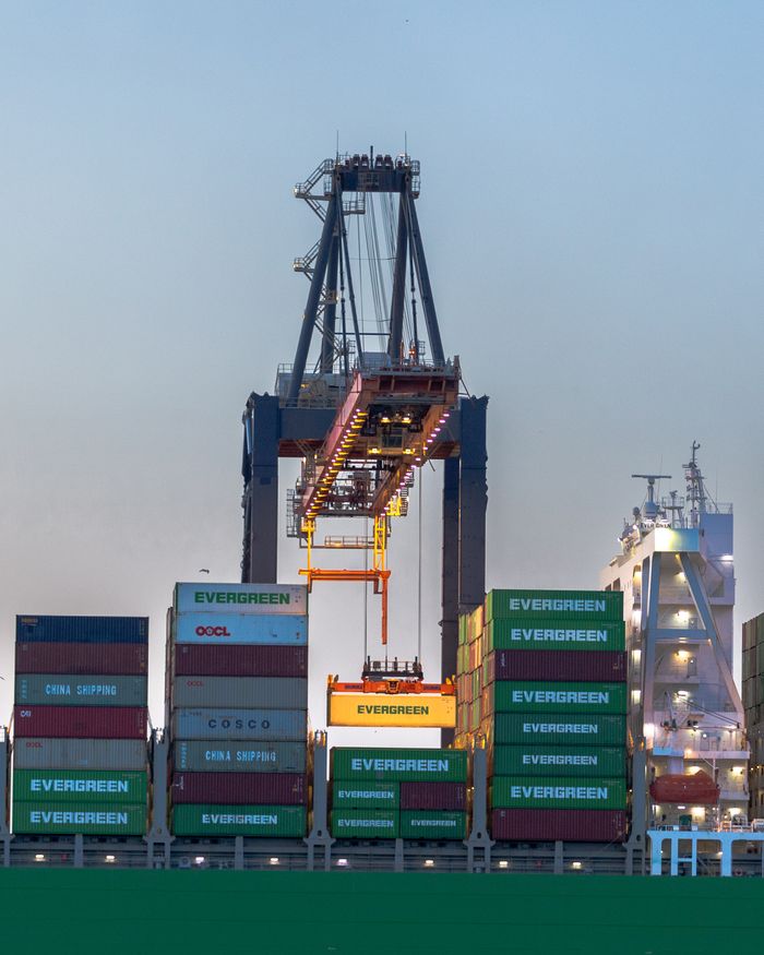 services-03 A busy container crane in Rotterdam port handling international cargo operations at dusk.